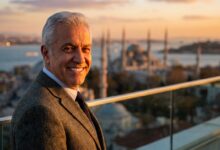 A close-up portrait of a happy, mature man with a brilliant, healthy smile. In the background, the Istanbul skyline is softly blurred during a beautiful sunset, symbolizing a successful dental tourism journey.