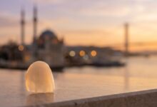 A close-up of a perfect dental veneer with the sunlit, blurred skyline of Istanbul, Turkey in the background, symbolizing a dental tourism and travel package.
