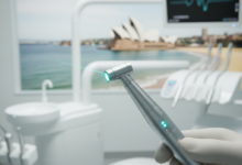 A photorealistic image showing a modern dental laser handpiece with a subtle light beam, held in a clean, high-tech dental clinic environment. The background features a softly blurred, iconic Australian landmark or a distinctive coastal view, subtly suggesting the location. The image emphasizes precision, innovation, and advanced dental technology.