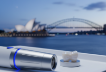 Close-up, detailed shot of a modern, sterile dental instrument or a perfectly crafted ceramic dental crown on a white surface, with a very blurred Australian city skyline or coastline in the background, conveying advanced dental care.