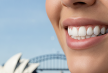 A photorealistic close-up of a person's healthy, natural smile, indicating successful dental restoration. In the softly blurred background, an iconic Sydney landmark like the Opera House or Harbour Bridge is visible. The image is bright, clean, and free of any text or branding.