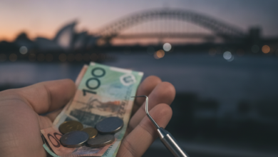 A close-up, photorealistic image of a hand holding blurred Australian dollar notes and coins, with a clean dental instrument in the foreground. In the soft-focus background, the iconic Sydney Opera House and Harbour Bridge are visible at dusk, symbolizing the financial burden of dental care in Australia.
