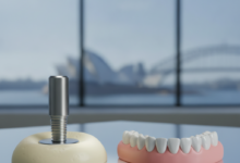 Conceptual visual comparing a metallic dental implant next to a gum-colored acrylic denture, both displayed on a sterile surface in a modern dental clinic. A very blurred iconic Australian landmark is visible in the background through a window. The image is clean, professional, and focuses on the two distinct dental solutions.